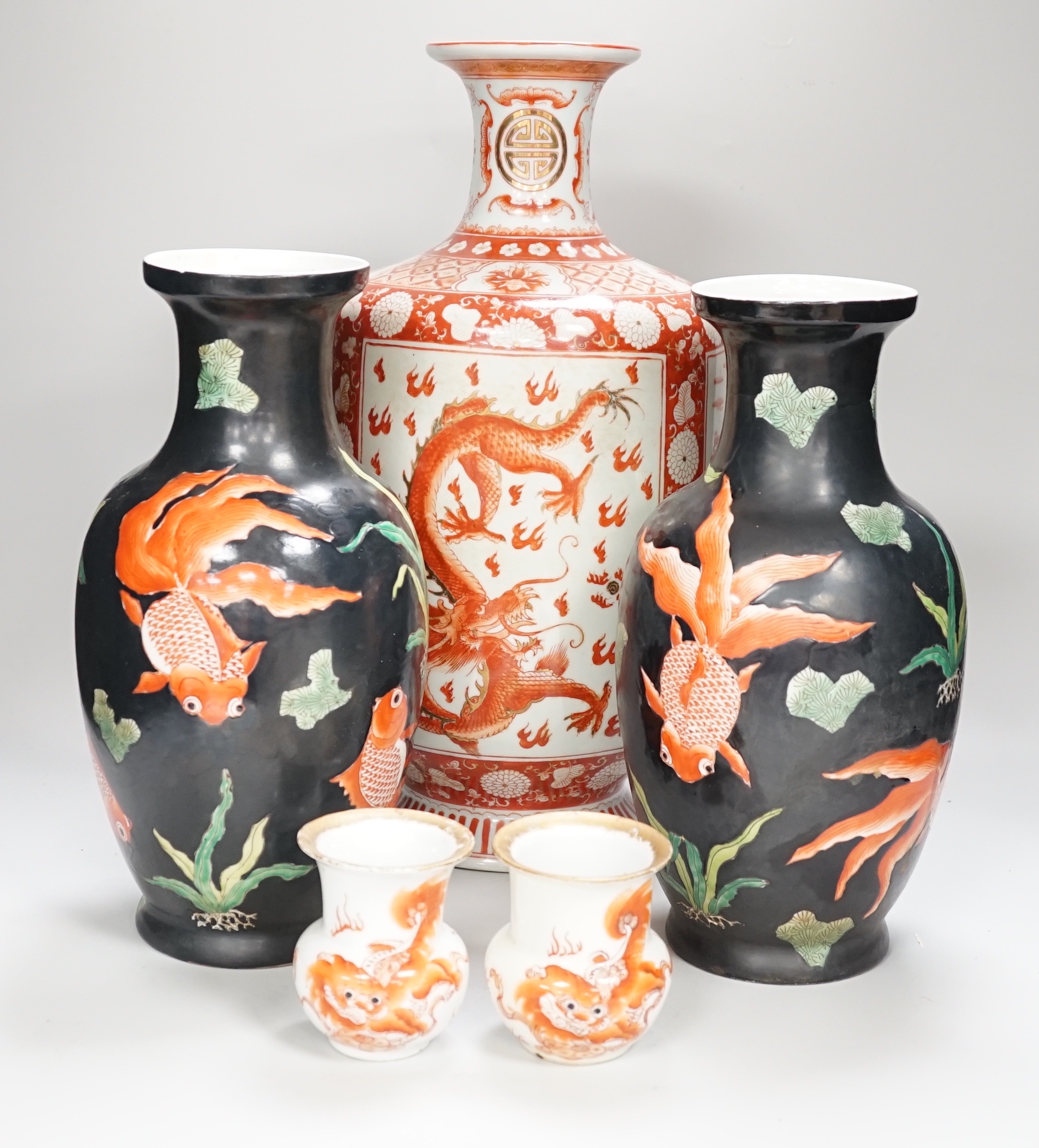 A Chinese iron red decorated ‘Dragon’ vase, a similar smaller pair of ‘Buddhist lion’ vases and a pair of black ground ‘goldfish’ vases, Republic period and later, tallest 42cm high